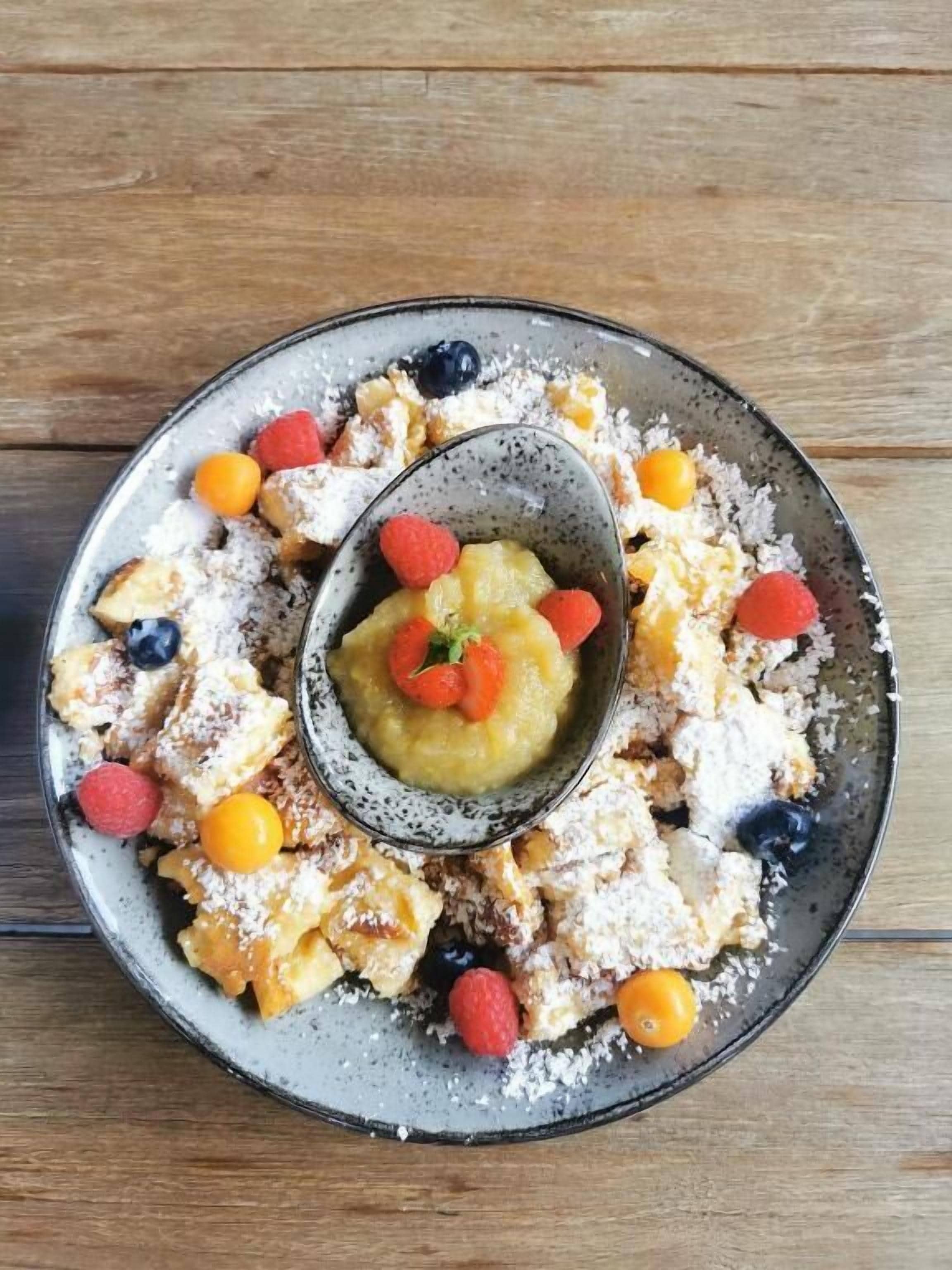 Un plato de comida con un bol central de fruta y pasteles alrededor.