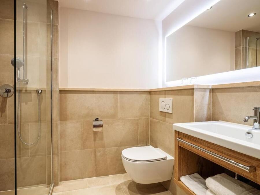 Un bany modern amb una dutxa de vidre, un vàter i un lavabo amb mirall.