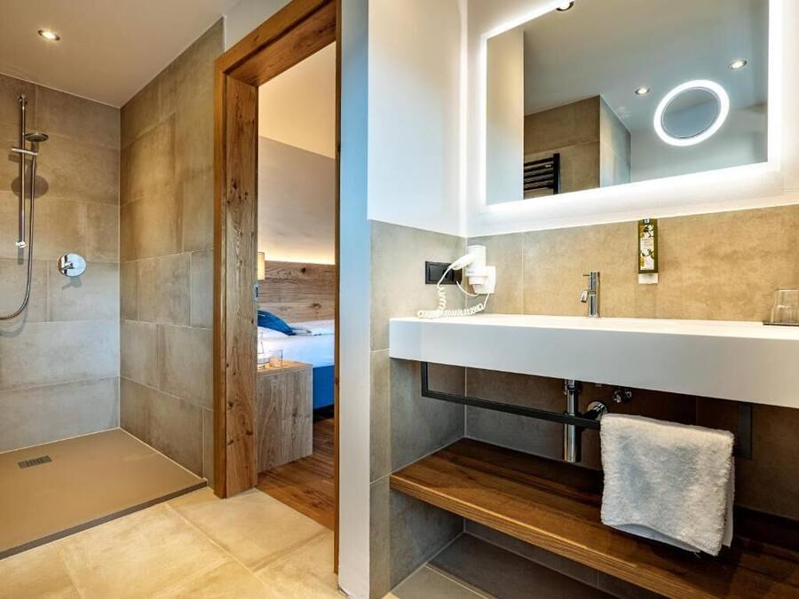 A modern bathroom with a shower, a vanity with a mirror, and a towel rack.