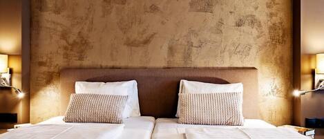 A double bed with two pillows, a textured wall, and bedside lamps.
