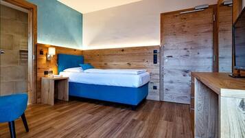 Um quarto moderno com cabeceira de madeira, cama com roupa de cama azul, mesa de cabeceira com abajur e guarda-roupa de madeira.