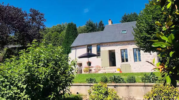 Een twee verdiepingen tellend huis met een grijs dak, een voordeur en een klein balkon.