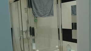 Ein modernes Badezimmer mit Duschkabine aus Glas, einem weißen Waschbecken und einem Spiegel mit schwarz-weißen Fliesen.