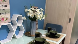 Uma mesa de jantar posta com tigelas e pratos pretos, um vaso com flores brancas e caixas de armazenamento brancas hexagonais.