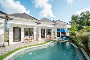 Uma casa moderna com piscina, área de estar externa e um jardim bem cuidado.