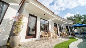 Ένα σύγχρονο σπίτι με πισίνα, εξωτερικό χώρο καθιστικού και φυτά σε γλάστρες.