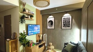 A modern living room with a flat-screen TV, a ceiling fan, and a sofa.