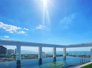 A rooftop infinity pool with a clear view of the ocean and cityscape.