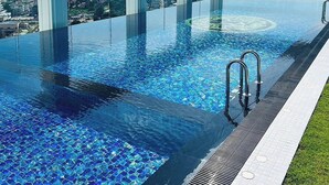 Una piscina infinita con agua azul cristalina, rodeada por un columnato blanco, y con vistas al paisaje urbano.