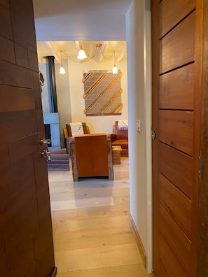 A hallway leading to a living area with a sofa, a coffee table, and a wall-mounted artwork.