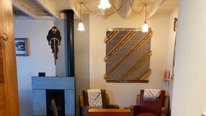 A room with a fireplace, wooden furniture, and hanging light fixtures. - Jasmine, pretty hat, on a bicycle (Bagnères-de-Luchon)