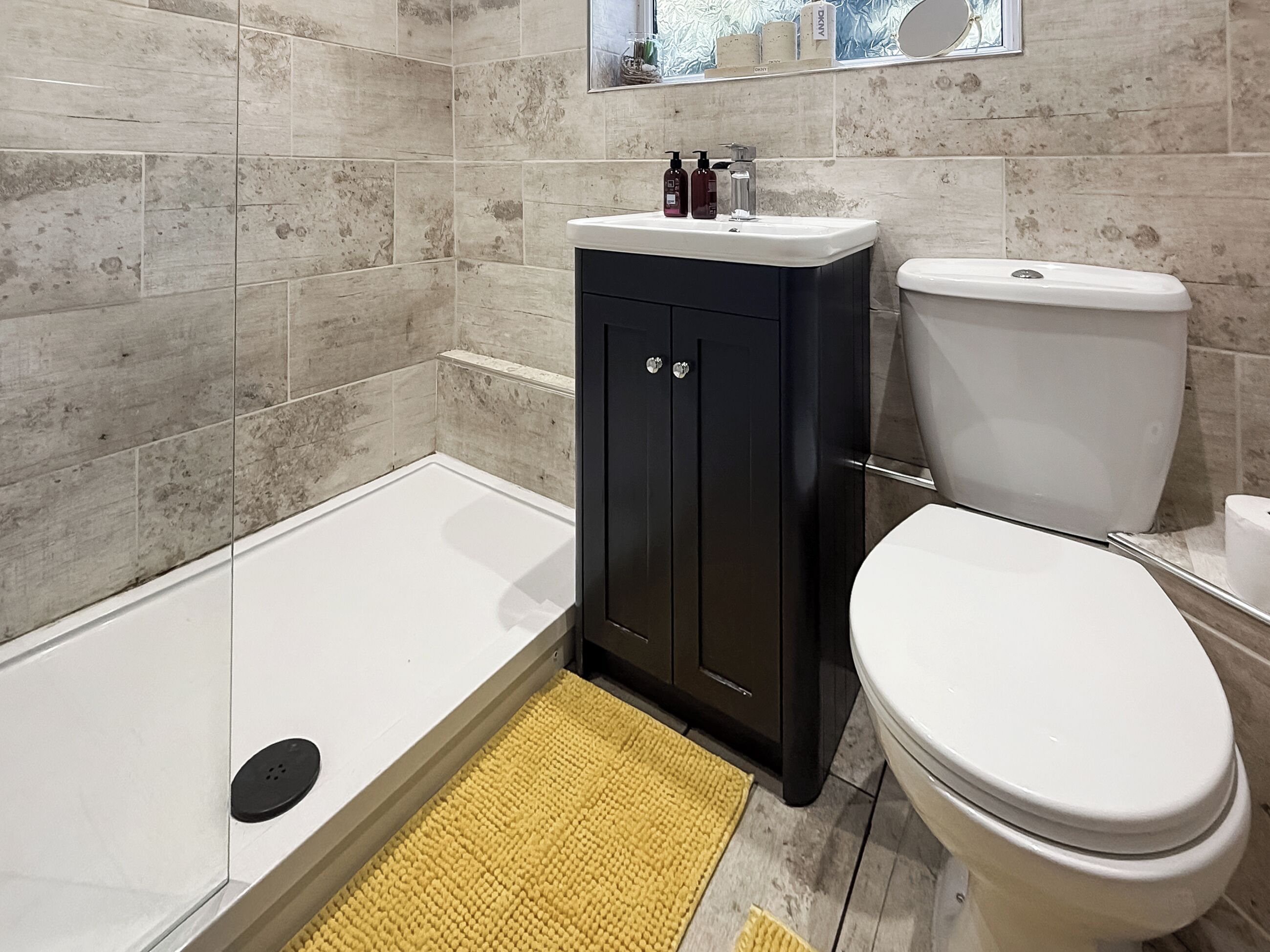 A bathroom with a white bathtub, a black cabinet, and a white toilet.