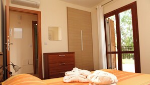 A bedroom with a bed, a wooden wardrobe, a bedside table, and a window with curtains. - 1 Bedroom Apartment - BC11 (kouklia)