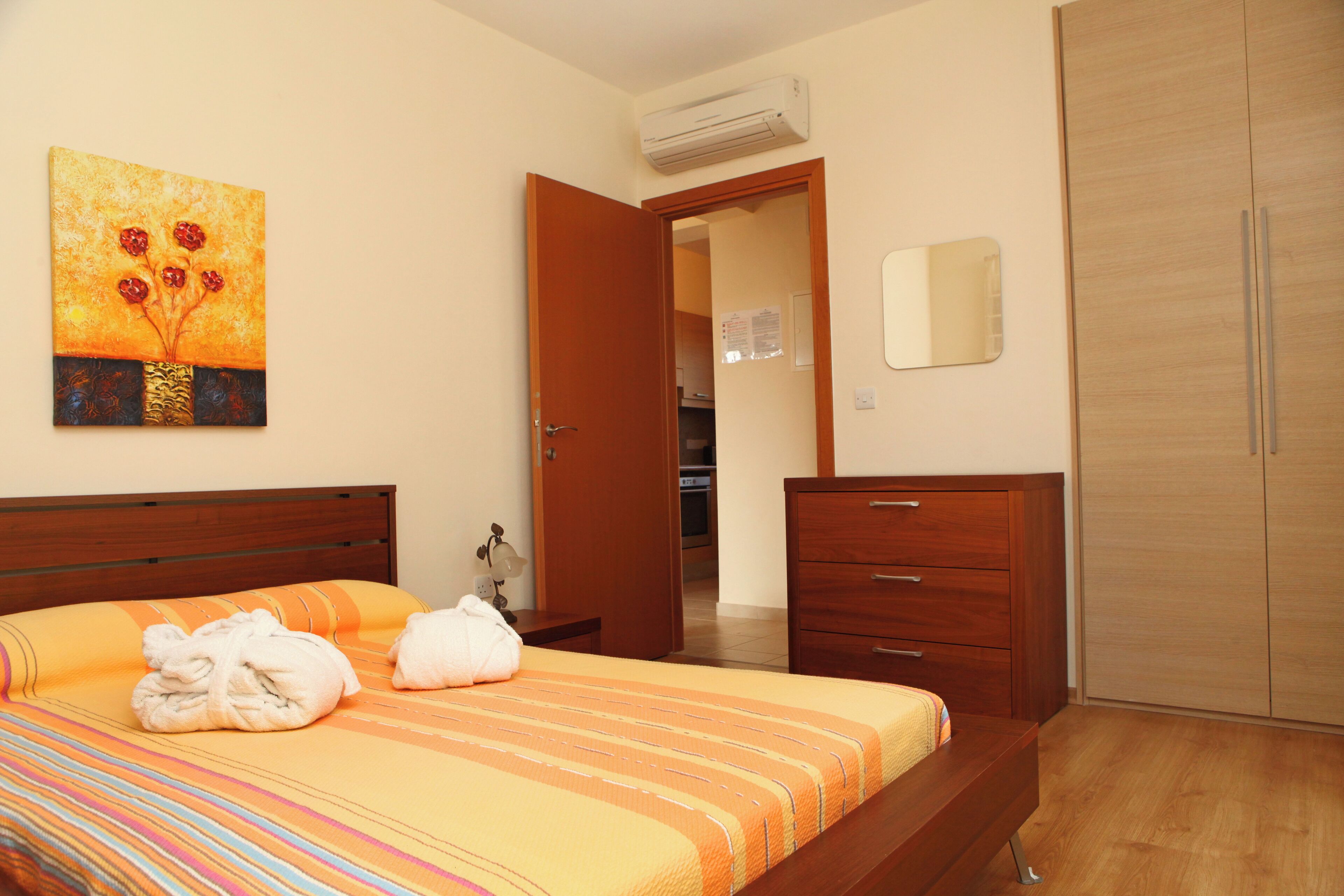 Ein Hotelzimmer mit einem Bett, einem Holzschrank, einem Spiegel und einer Klimaanlage.