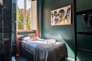 Una habitació amb llit, finestra, quadre i porta.