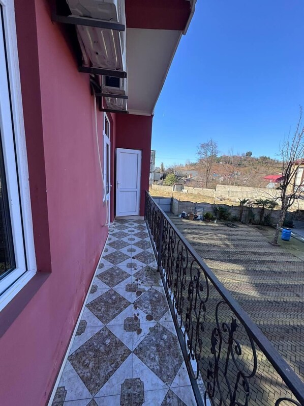 A red building with a tiled balcony and a white door. - Llia hotel  (Kobuleti)