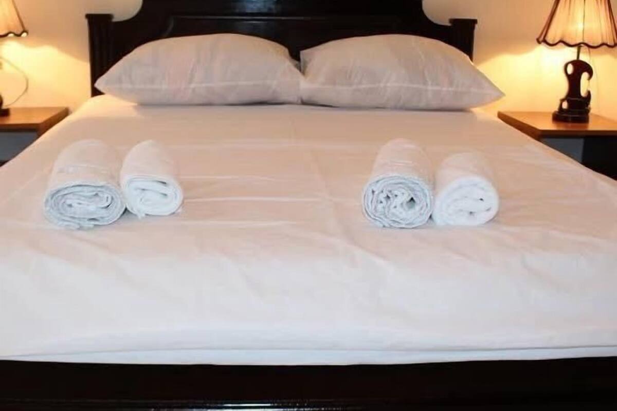 A neatly made bed with two rolled towels placed on the bed.