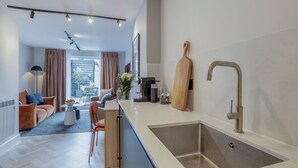 Une cuisine moderne dotée d’un grand îlot central, d’un évier en acier inoxydable et d’une planche à découper en bois.