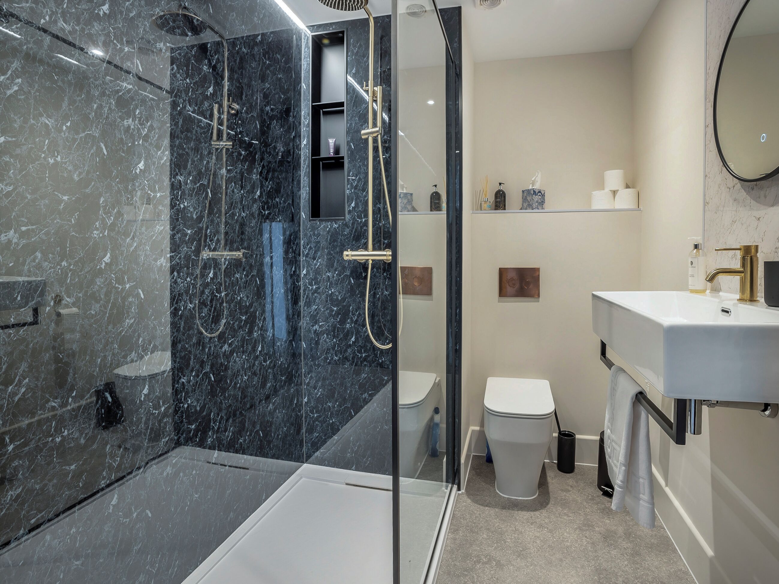 A modern bathroom with a glass-enclosed shower, a white toilet, and a vanity with a gold faucet.