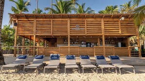 A beachside wooden structure with a bar area and multiple lounge chairs.