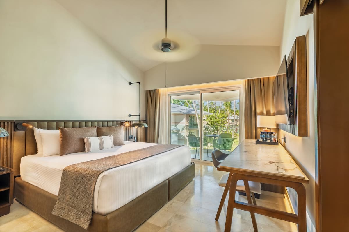 Ein Hotelzimmer mit einem großen Bett, einem Esstisch und einem Balkon mit Sitzgelegenheit.