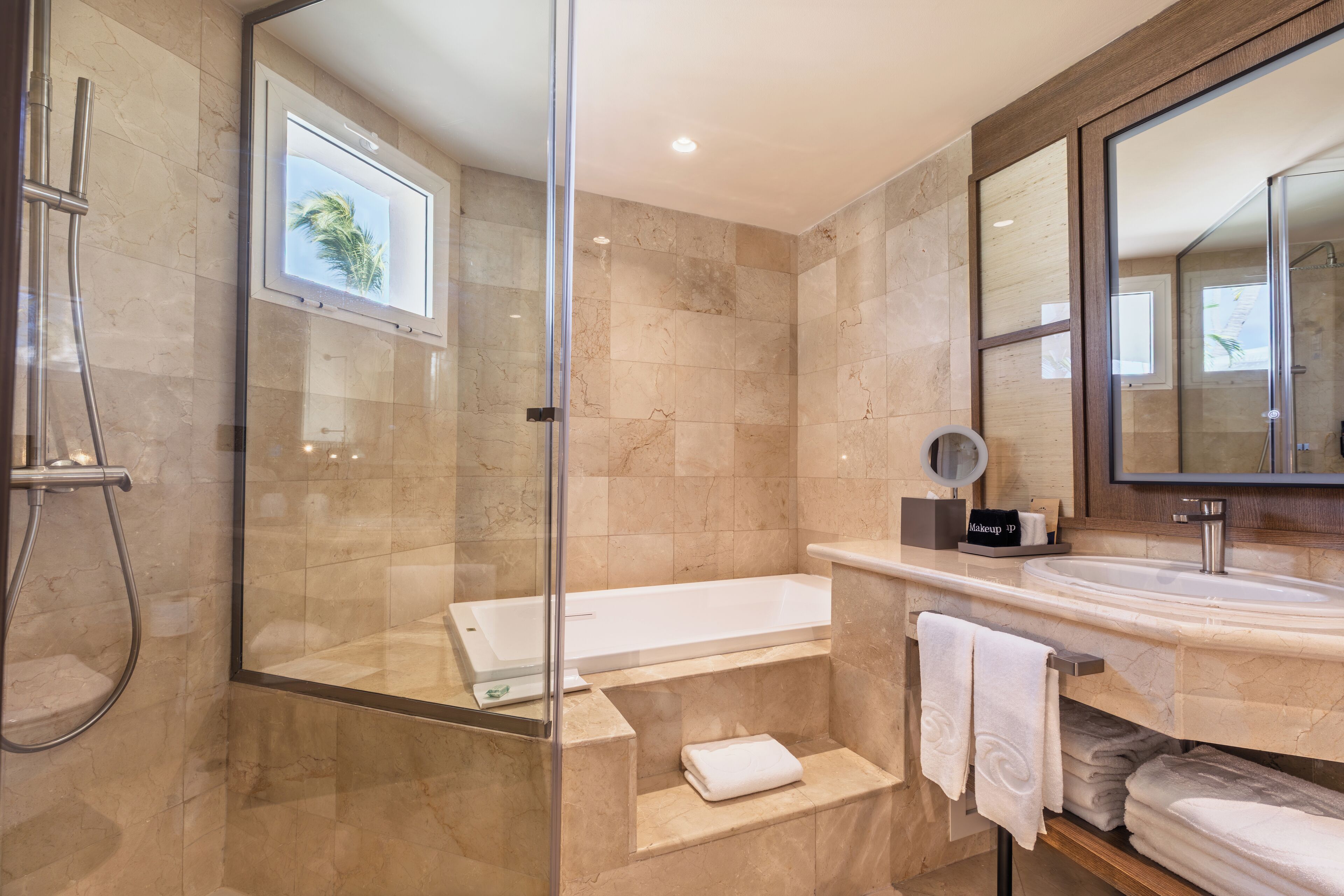 A modern bathroom with a glass-enclosed shower, a freestanding bathtub, and a vanity with a large mirror.