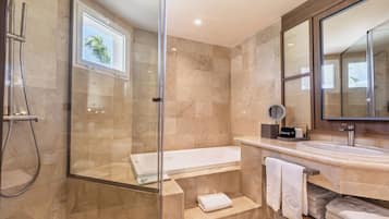 Ein modernes Badezimmer mit einer begehbaren Glasdusche, einer freistehenden Badewanne und einem Waschbecken mit einem großen Spiegel.