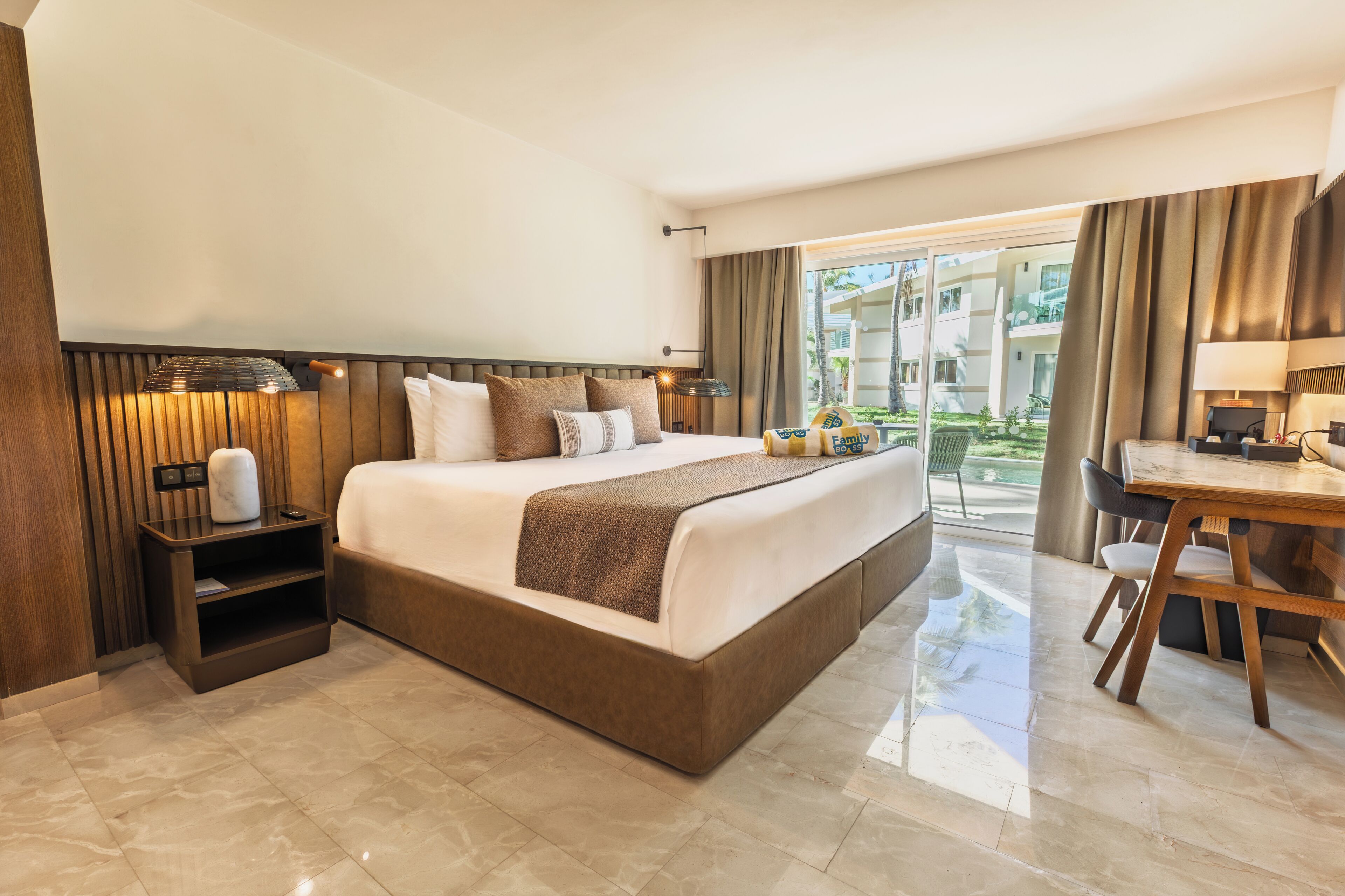 Une chambre d’hôtel avec un grand lit, un bureau, une chaise, une table de chevet et une vue sur l’extérieur.