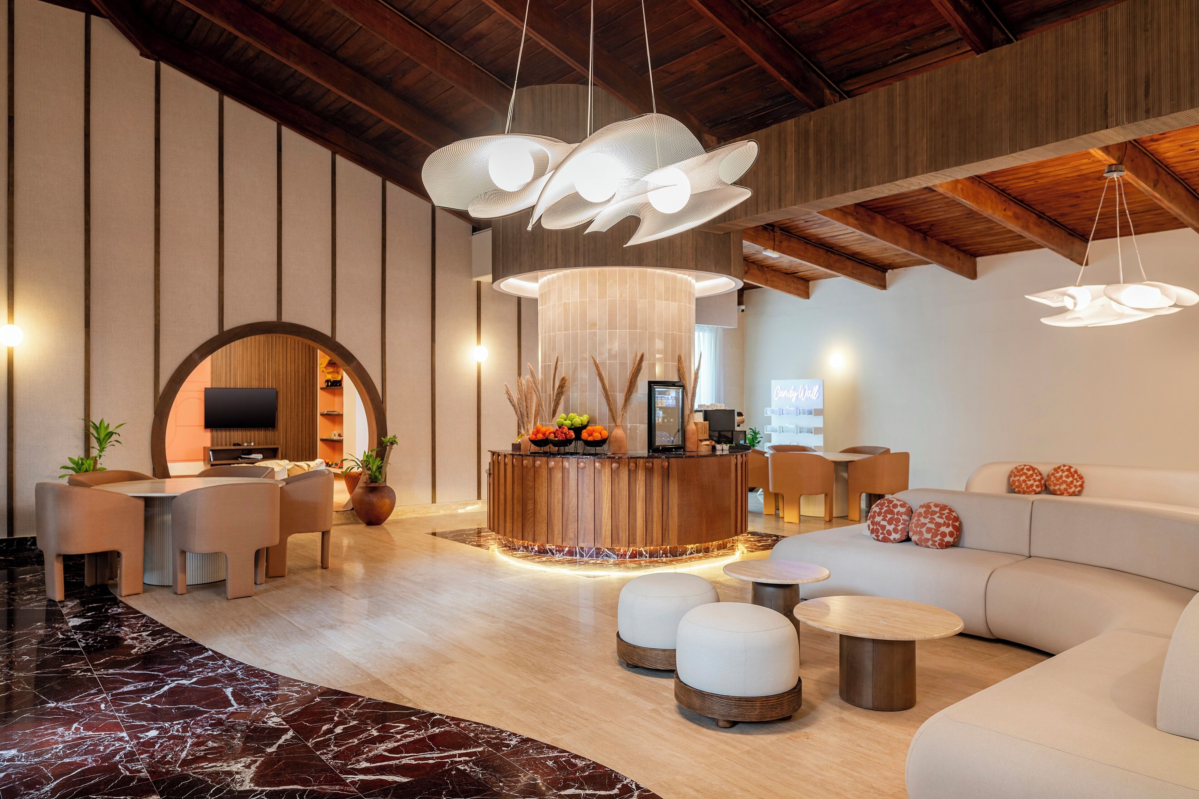 A modern lobby with a reception desk, seating area, and a large chandelier.