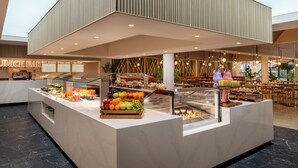 A buffet area with a juice bar, various fruits, and a seating area with tables and chairs.