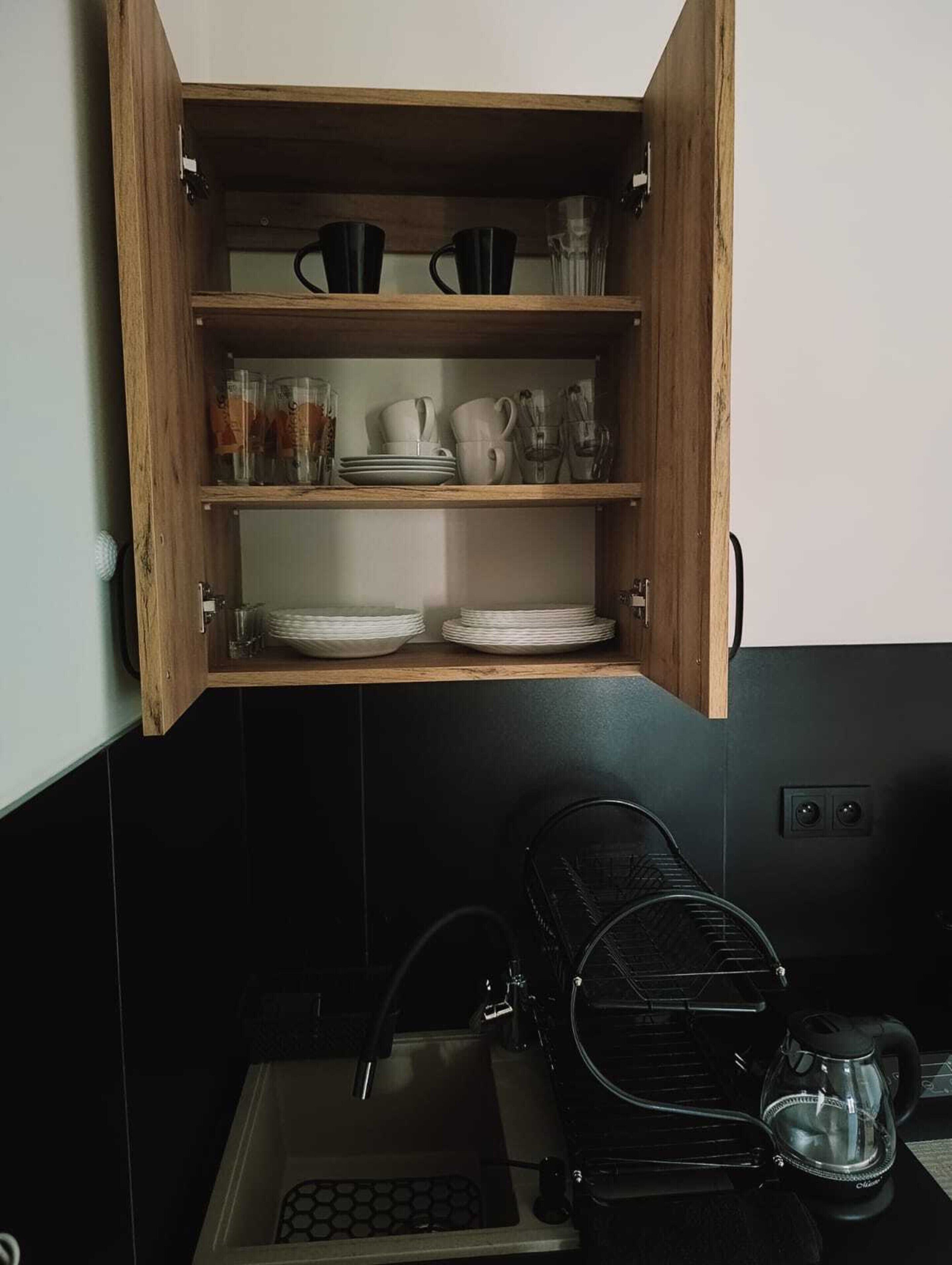 Une cuisine avec un meuble en bois contenant de la vaisselle et des verres.