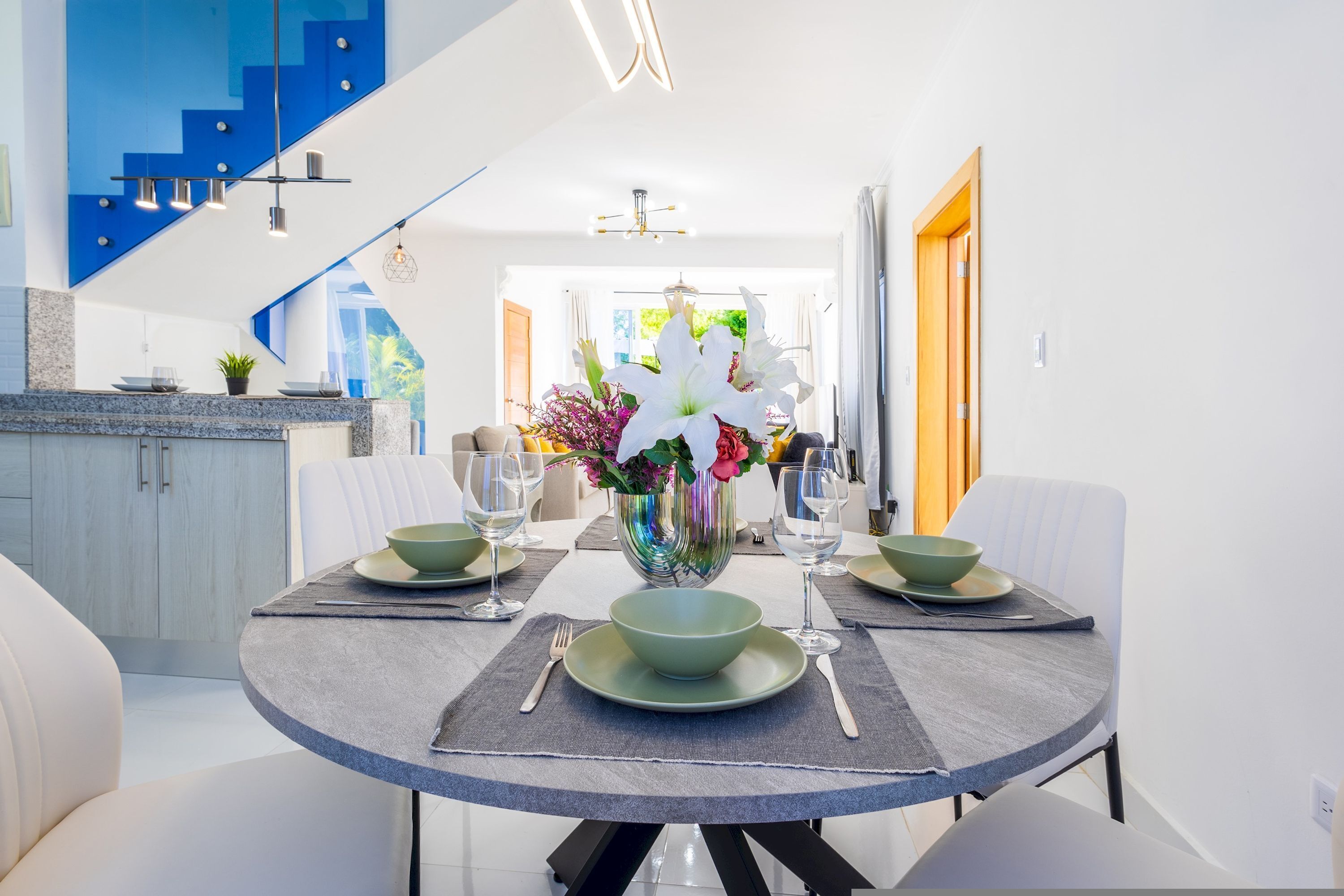 A dining area with a round table, green plates, and a vase of flowers.
