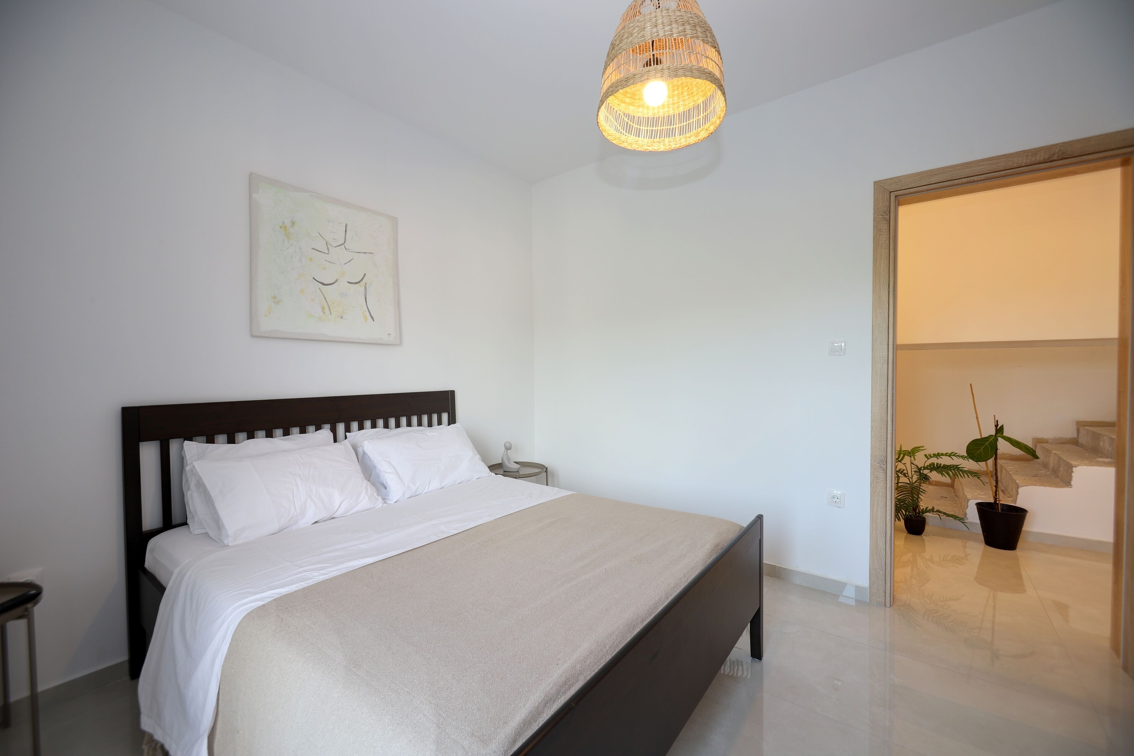 Un dormitorio con cama, mesita de noche y lámpara colgante.