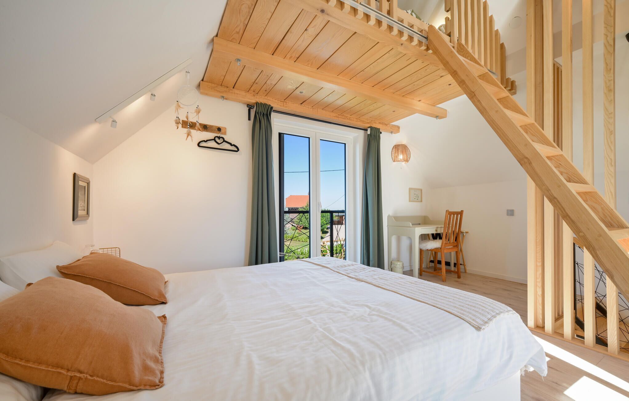Une chambre avec un grand lit, un escalier en bois et un bureau avec une chaise.