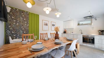 Een moderne keuken met witte kasten, een houten eettafel en een groene accentmuur.