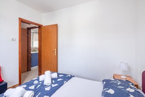 A hotel room with a bed, a bedside table, a lamp, and a bathroom visible through an open door. - Peaceful Retreat Apartments With Terrace (Marcana)