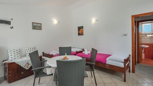 Une pièce comprenant un lit, une table à manger avec des chaises, un petit meuble et une salle de bain visible à travers une porte ouverte.