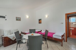 A room with a bed, a dining table with chairs, a small cabinet, and a bathroom visible through an open door. - Peaceful Retreat Apartments With Terrace (Marcana)