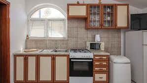 Une cuisine avec des meubles de rangement en bois, une cuisinière, un four à micro-ondes et un réfrigérateur.