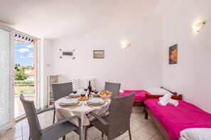 A room with a dining area, a bed with a pink bedspread, and a painting on the wall. - Peaceful Retreat Apartments With Terrace (Marcana)