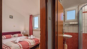 Une chambre avec un lit, une fenêtre et une salle de bain équipée d’un lavabo et d’une douche.