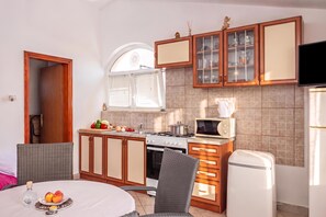 A compact kitchen with a stove, microwave, and cabinets. - Peaceful Retreat Apartments With Terrace (Marcana)