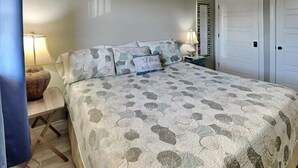 Ein Schlafzimmer mit einem Bett, zwei Nachttischen, einer Lampe und zwei Türen.