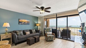 Ein Wohnzimmer mit einer Couch, Sesseln und einem Deckenventilator.