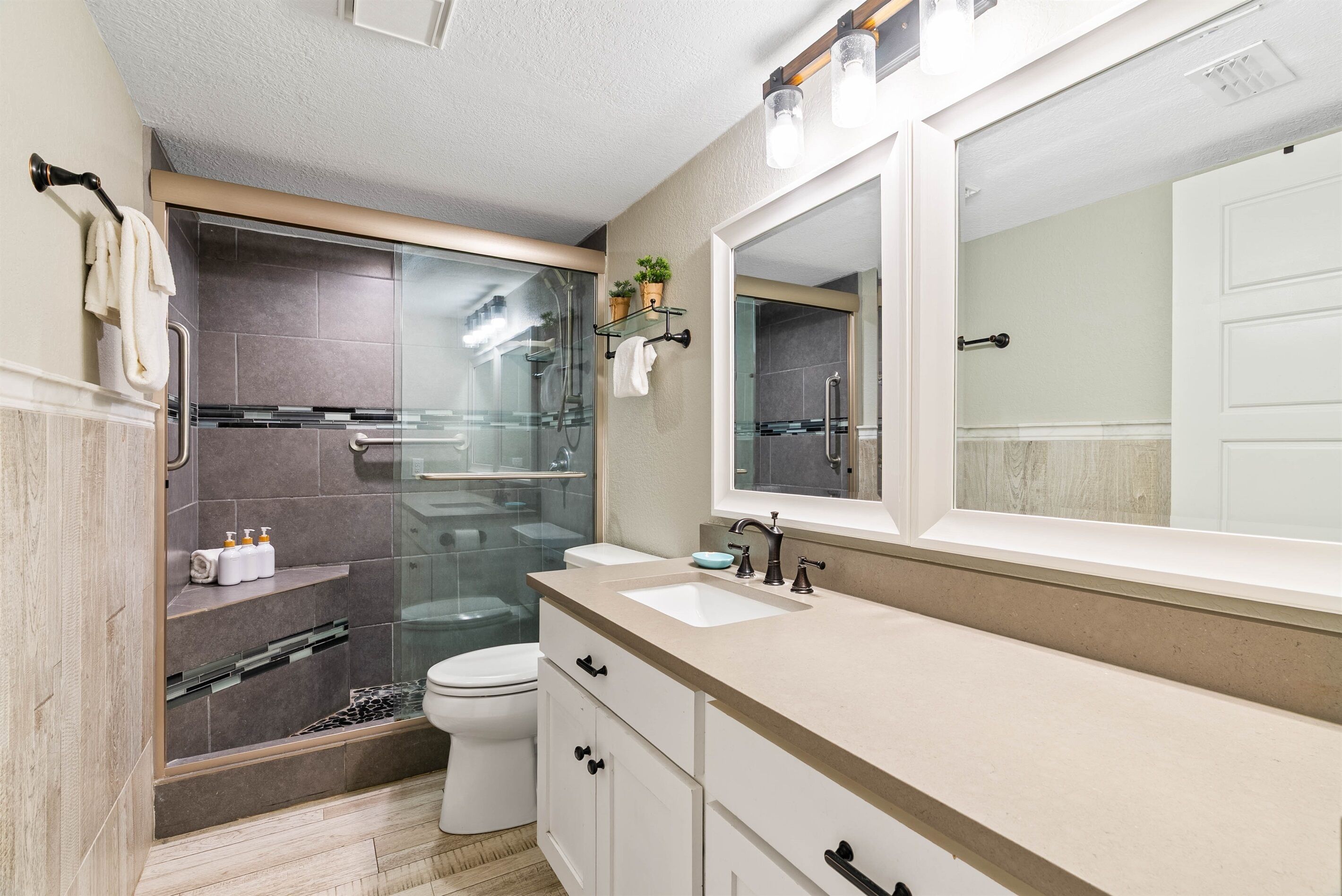 A modern bathroom with a glass-enclosed shower, a large mirror, and a white sink.