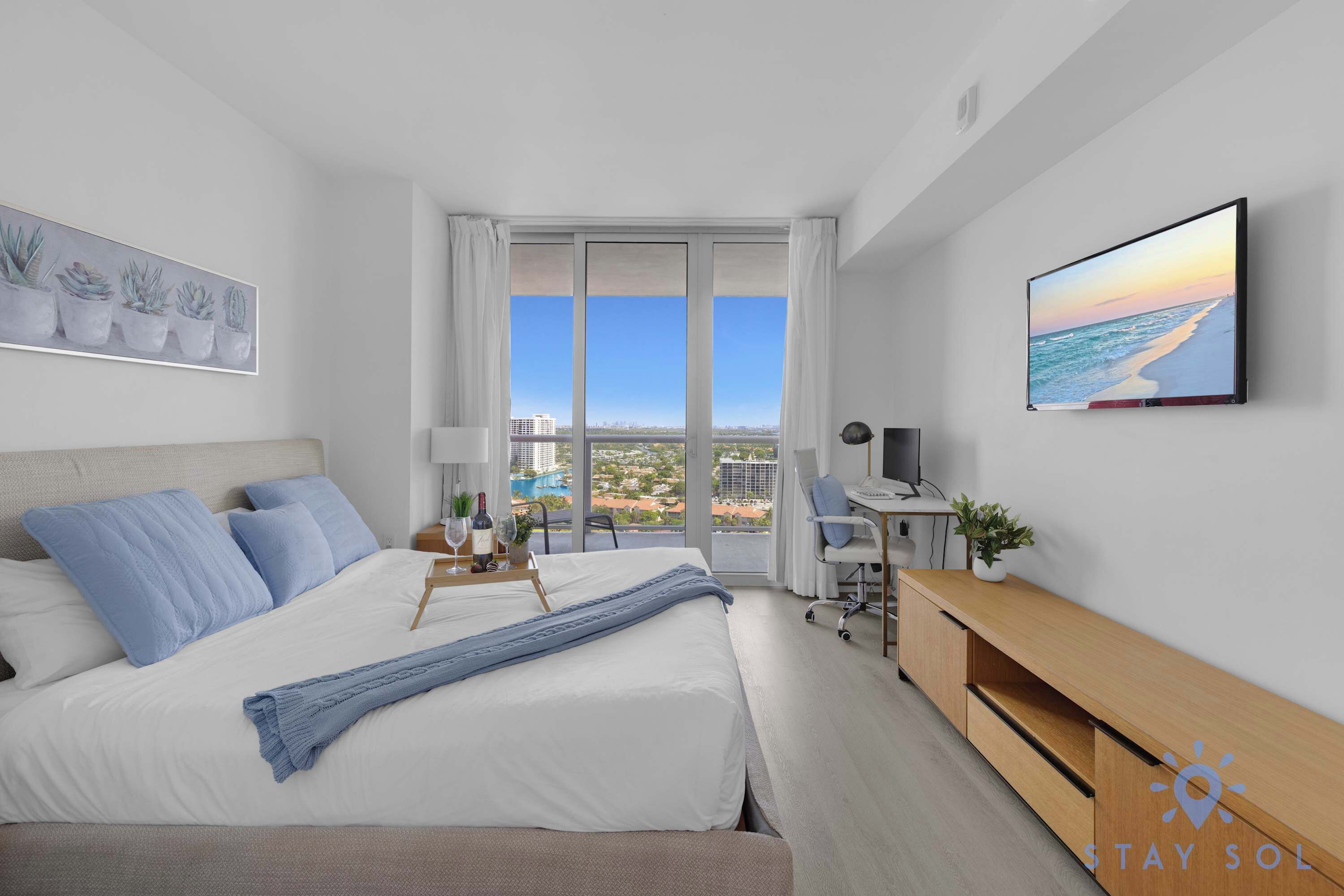 Habitación de hotel moderna con una cama grande, un escritorio y vistas a la ciudad desde la ventana.