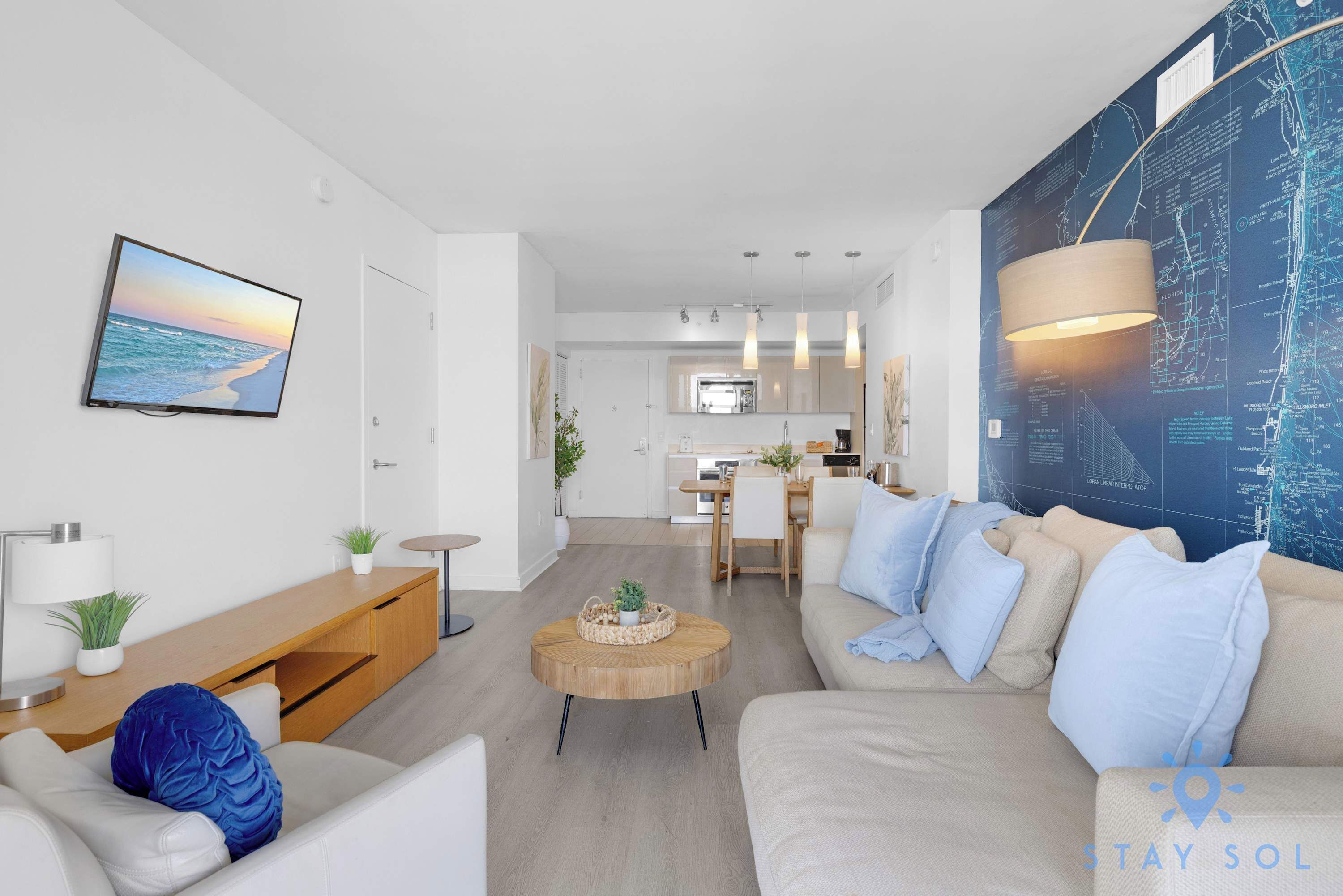 Una sala de estar moderna con un sofá, una mesa de centro y un televisor montado en la pared.