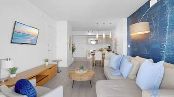 Una sala de estar moderna con un sofá, una mesa de centro y un televisor montado en la pared.