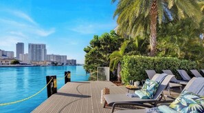 A poolside area with lounge chairs, a table with drinks, and a view of the city skyline.