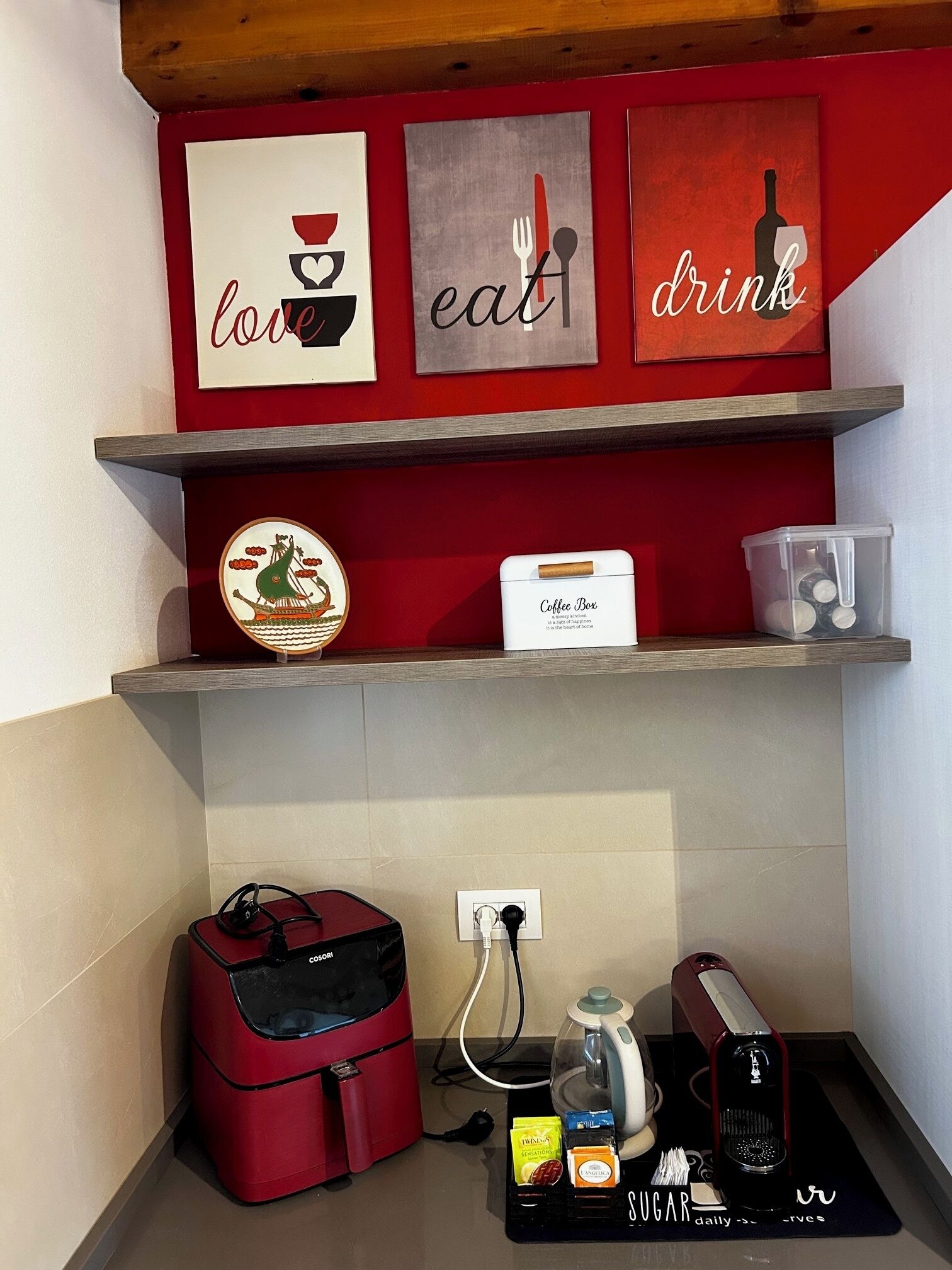 A kitchen area with a coffee maker, sugar packets, and a coffee box on the counter.